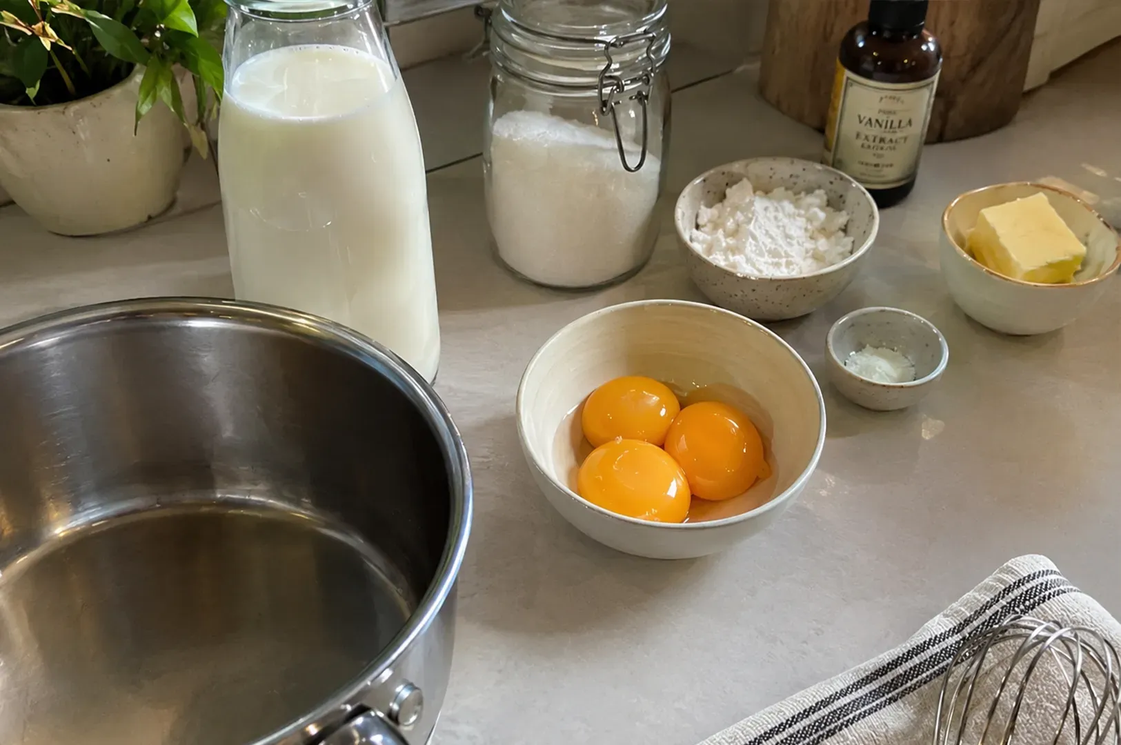 Ingredients for baking on a kitchen counter: eggs, milk, flour, butter, and a mixing bowl.