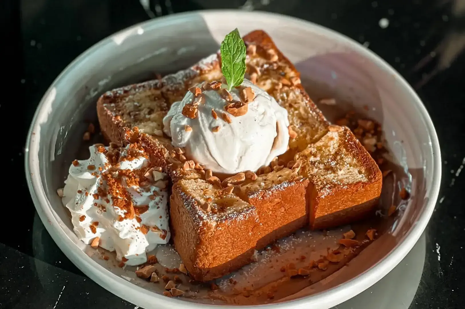 Chocolate cake topped with whipped cream and mint in a white bowl