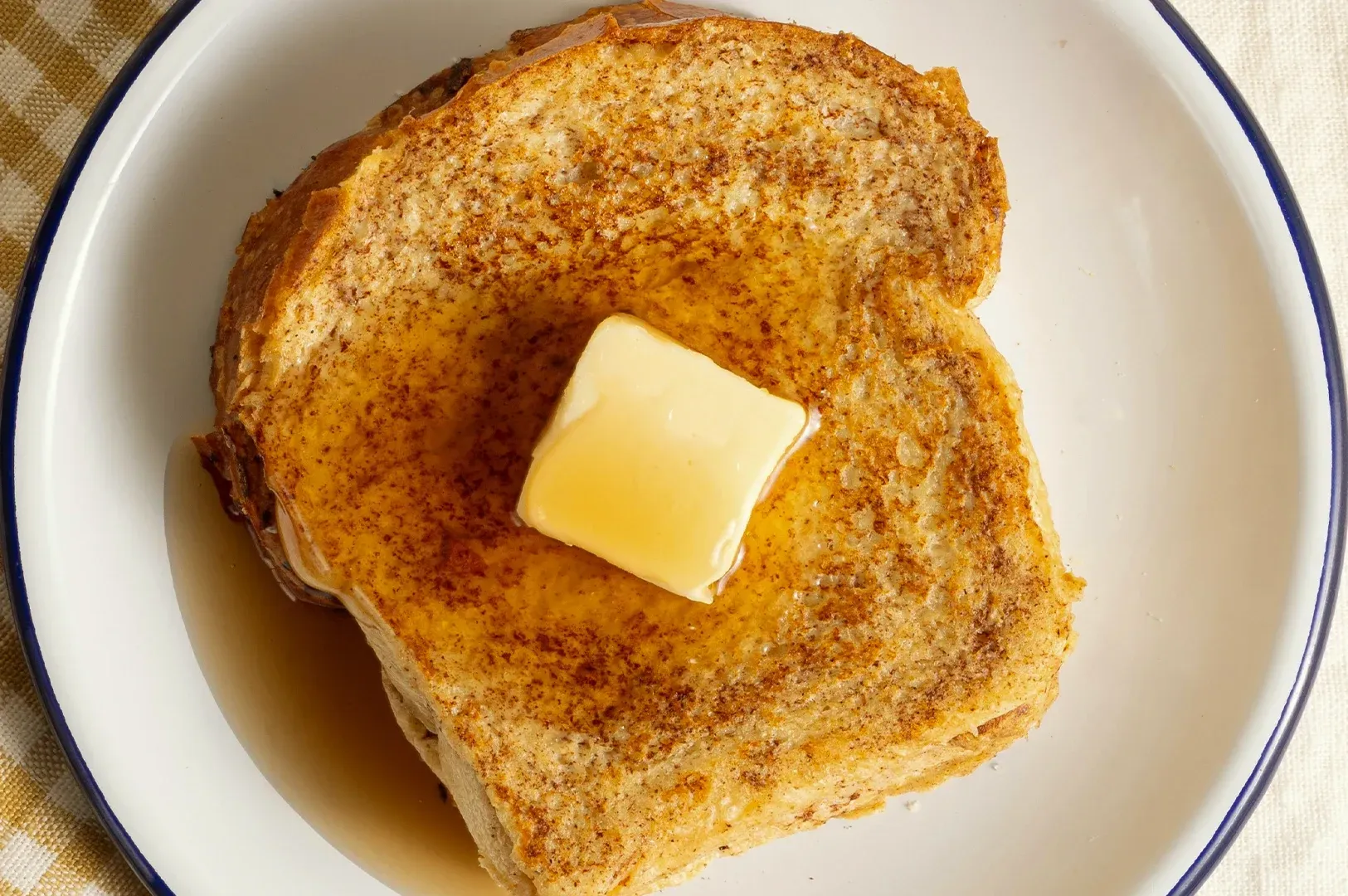 Toasted bread topped with a pat of butter on a white plate