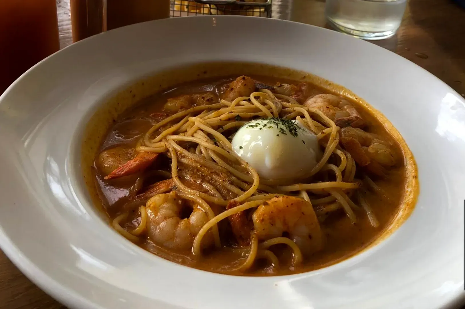 Bowl of spaghetti in rich red sauce topped with a poached egg on a white plate