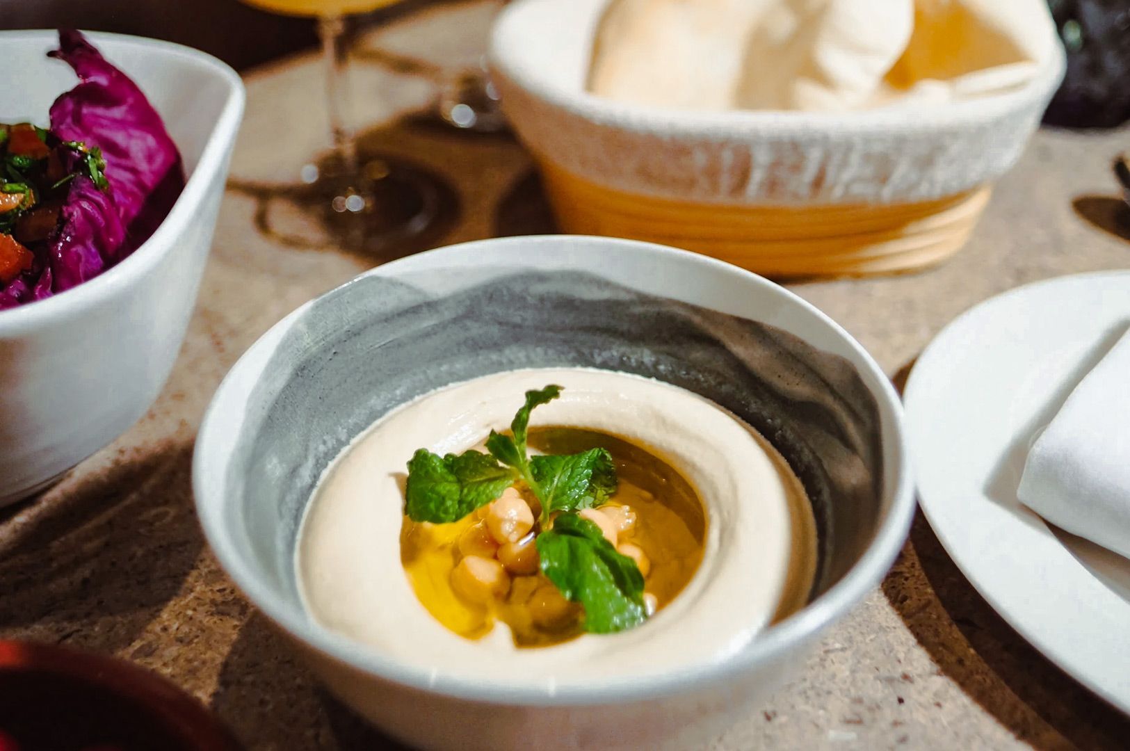 Creamy soup in a gray bowl, garnished with herbs and yellow sauce on a wooden table.