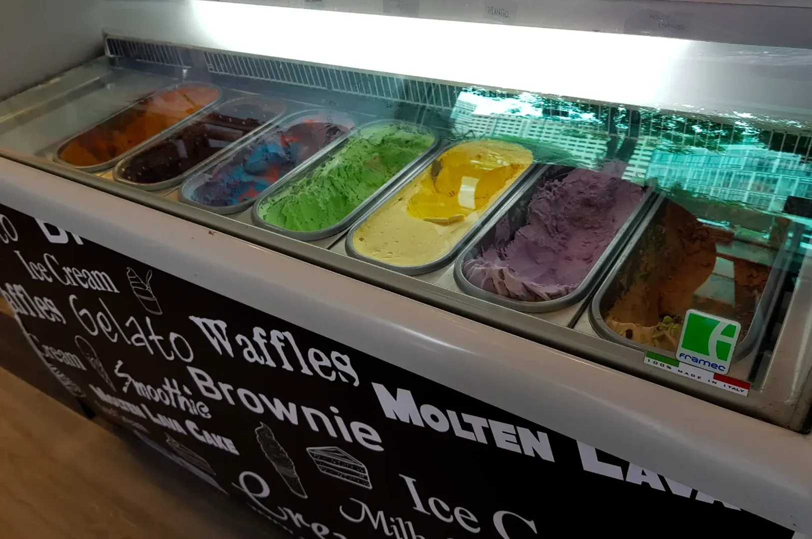 Ice cream toppings bar with colorful scoops and menu signs for waffles, molten lava brownie, and ice cream treats