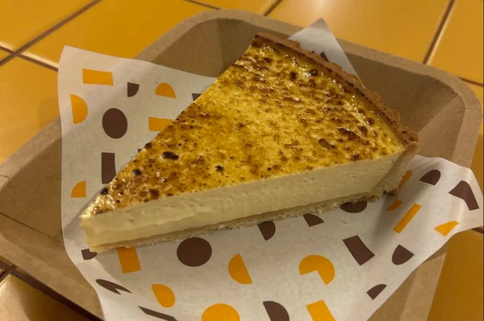 Slice of toasted pie in a cardboard tray with patterned paper lining