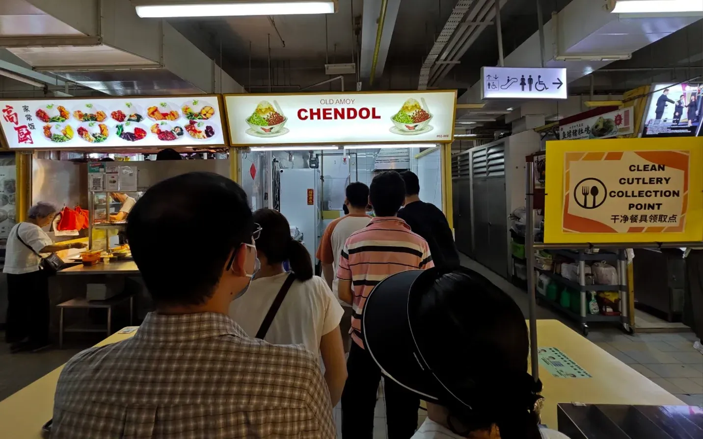 People waiting in a covered food court walkway near a stall labeled “CIENDOL.”