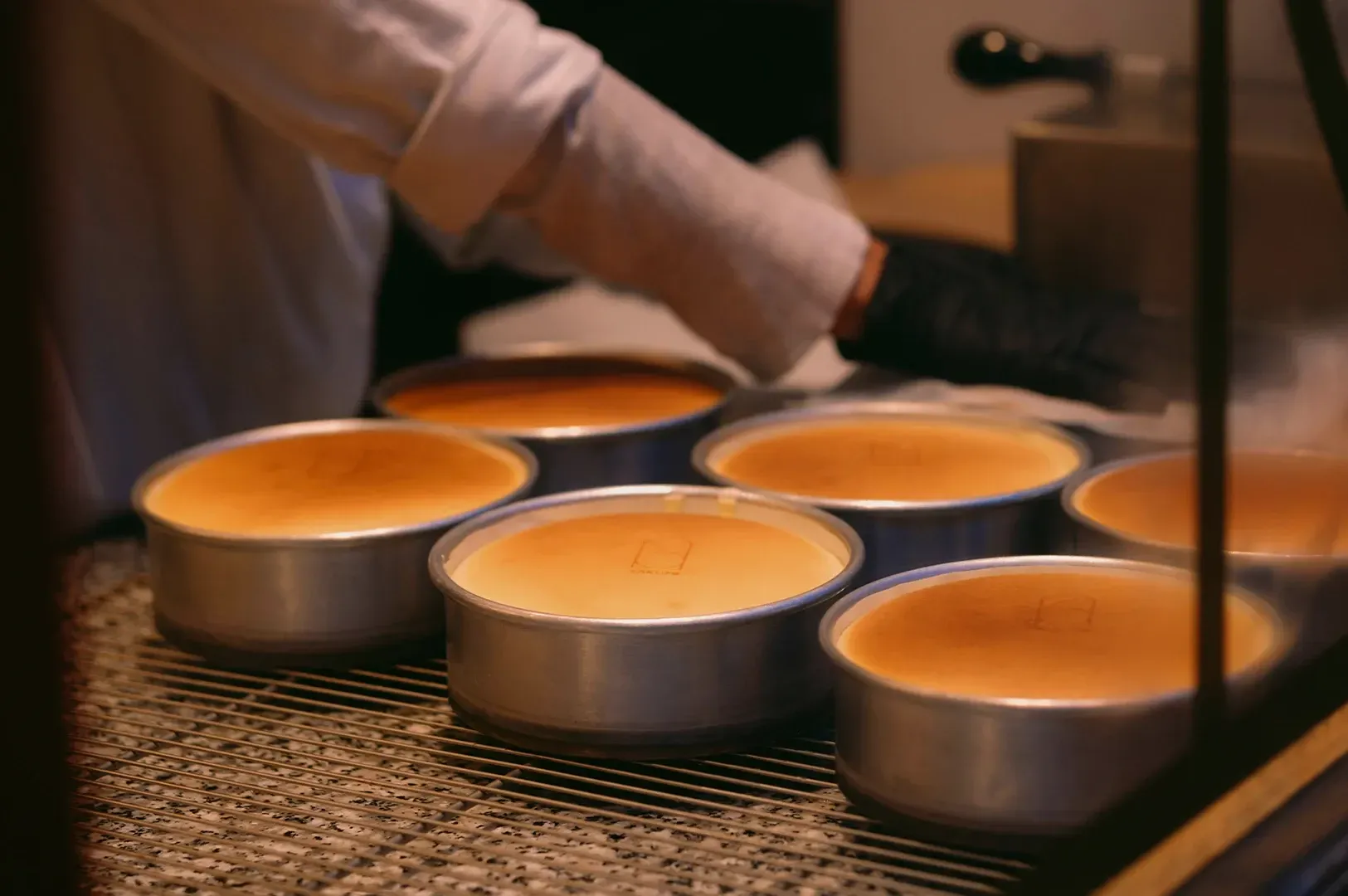 Candle wicks being trimmed over a row of lit tea light candles on a table