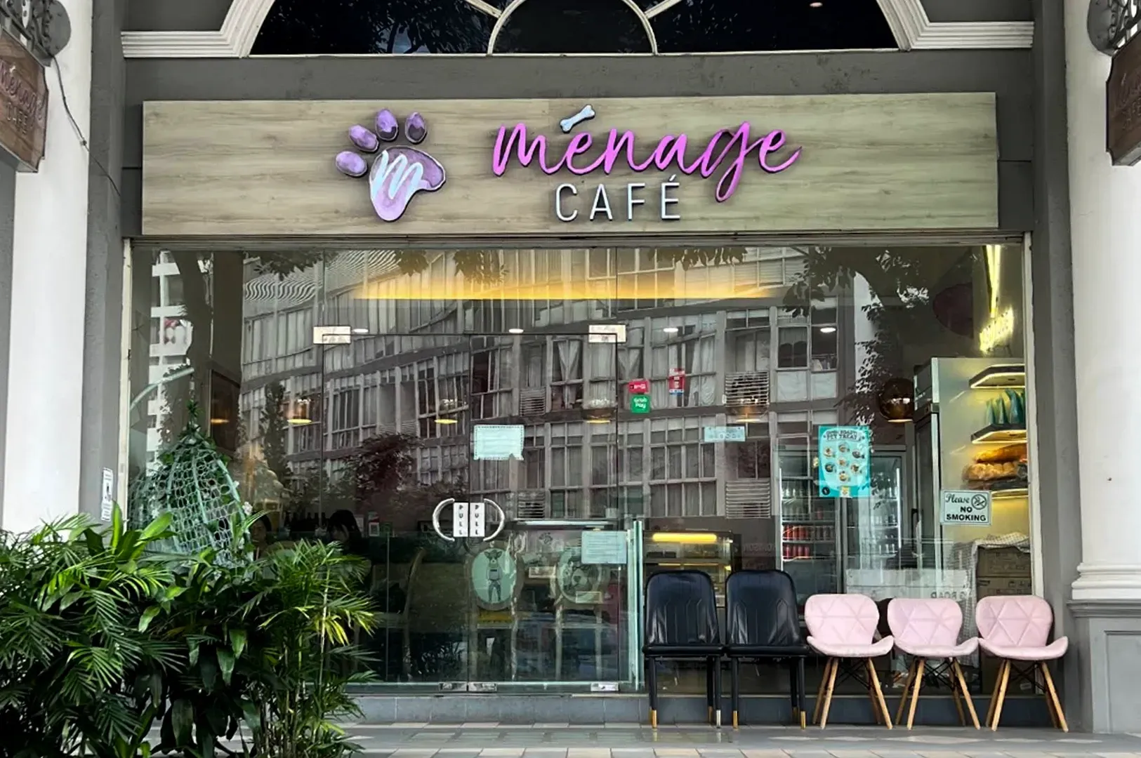 Exterior of Pinkage Cafe with glass front, purple signage, and pink chairs outside