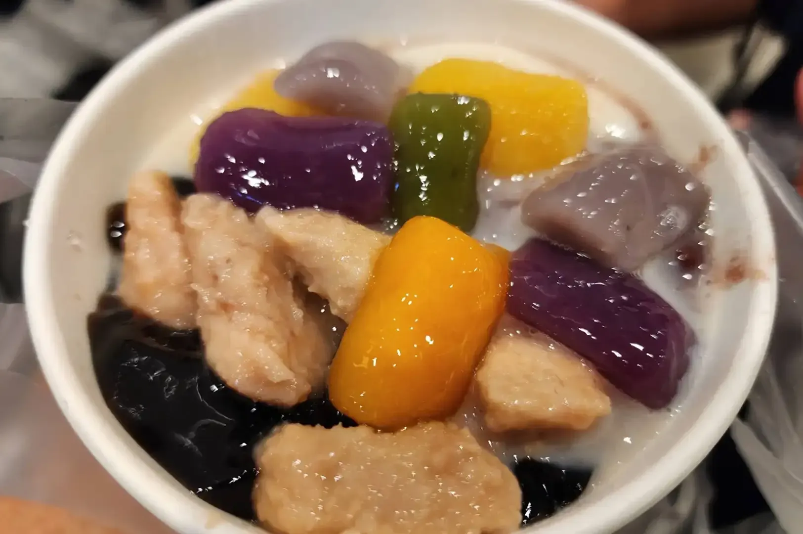 Bowl of colorful dessert with taro, pumpkin, and rice cake pieces in sweet syrup