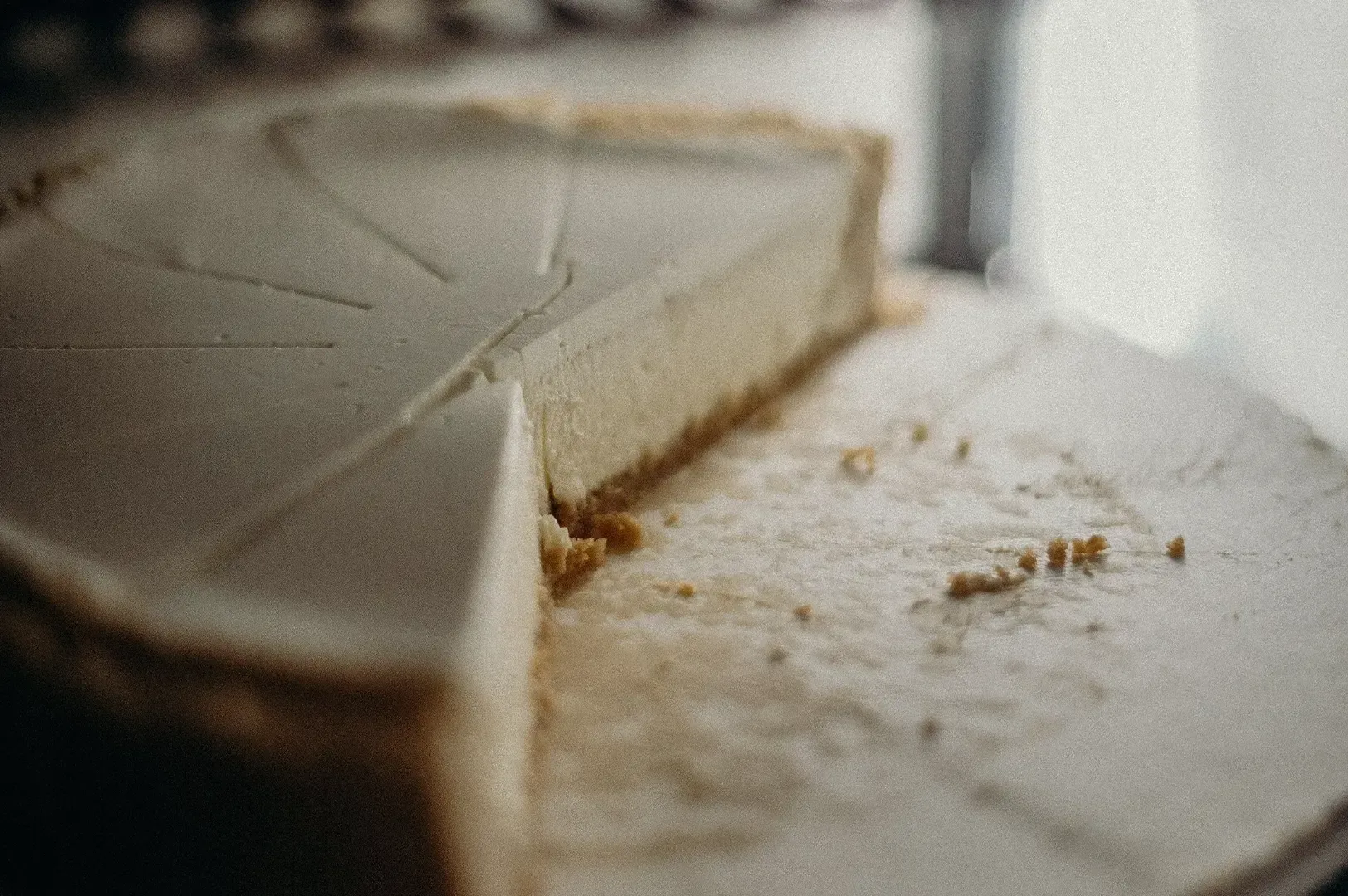 A partially eaten frosted cake slice on a white plate, with crumbs scattered nearby.