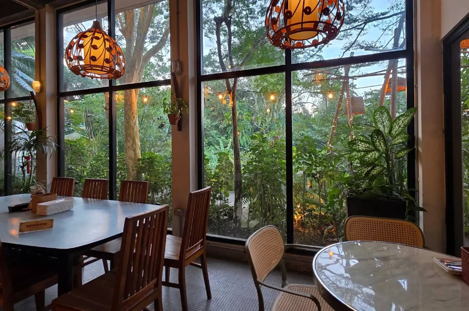 Cozy dining room with large windows overlooking lush greenery and hanging pendant lights
