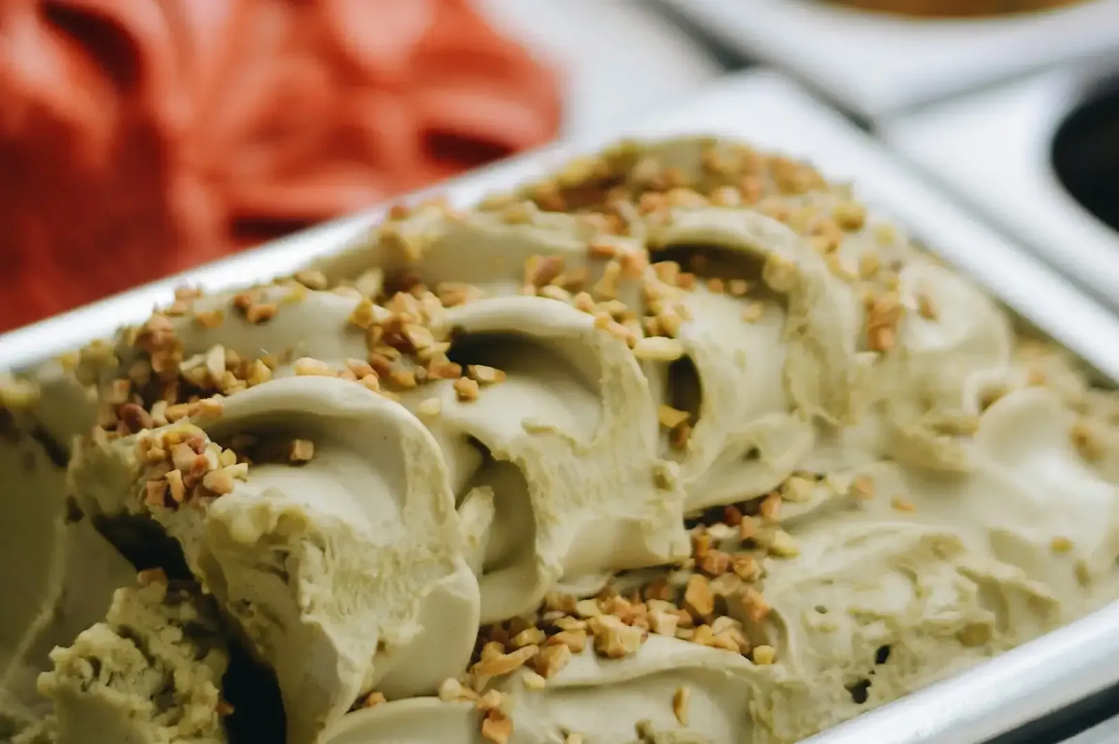 Tray of pale green ice cream scoops topped with chopped nuts on a white platter