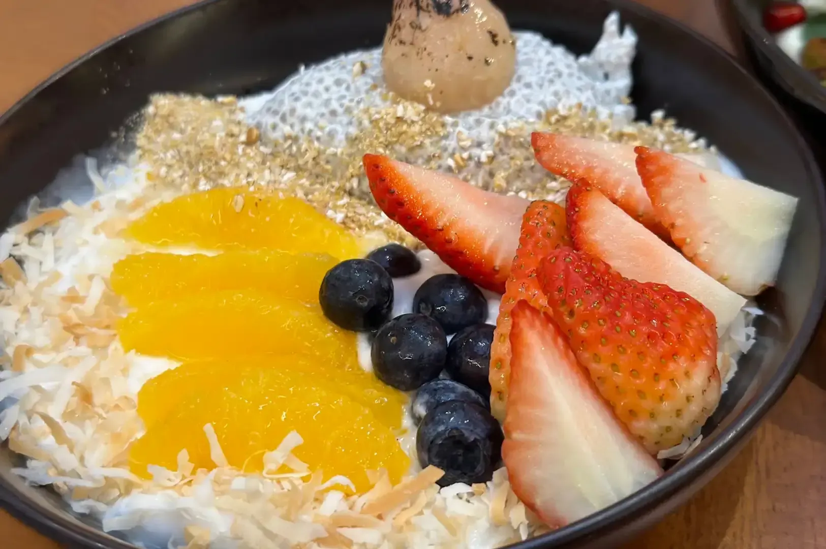Fruit-topped rice pudding bowl with mango, strawberries, blueberries, coconut, and a cookie topping