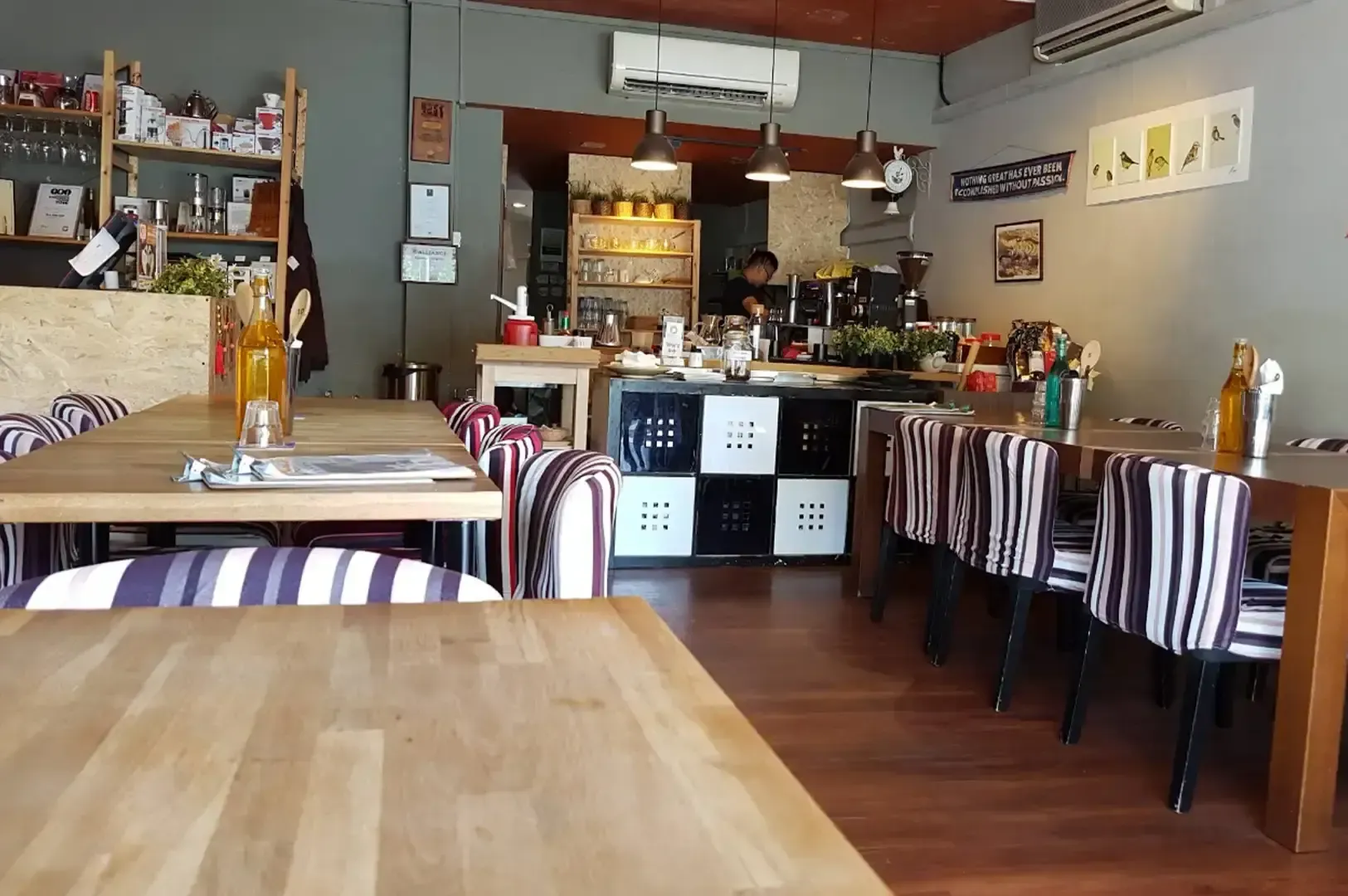Cozy restaurant dining area with striped chairs, wooden tables, and a bar counter in back