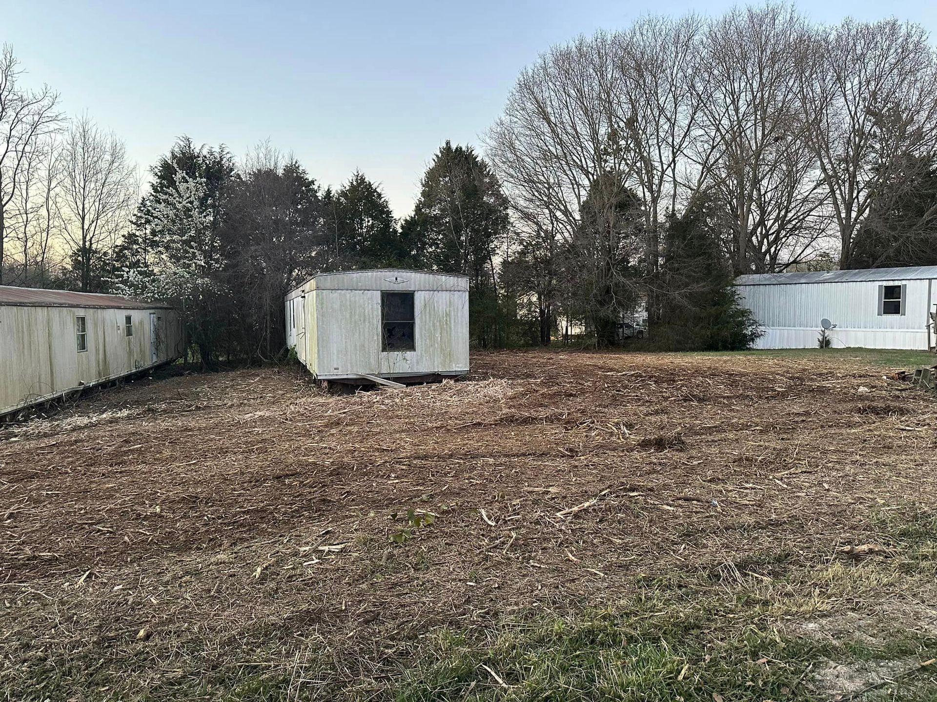 There are two mobile homes in the middle of a field.
