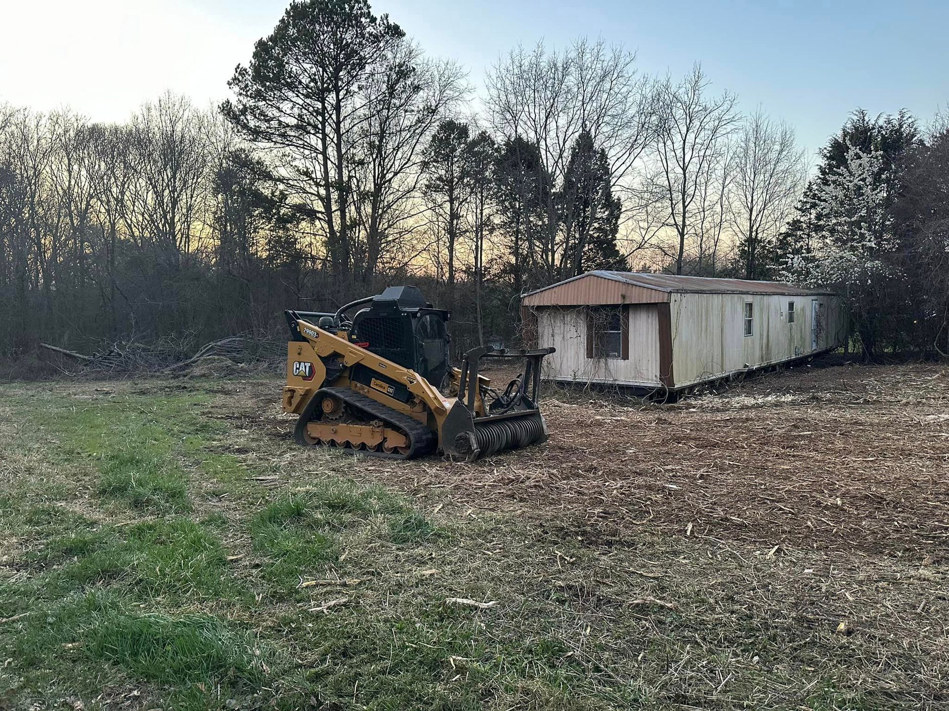 A bulldozer is sitting in a field next to a house.