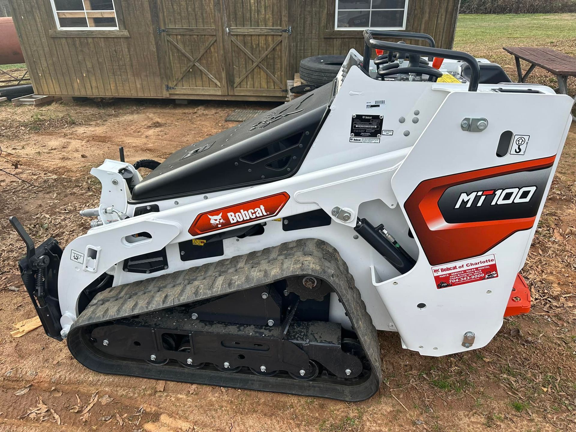 A bobcat mt100 compact track loader is parked in a dirt field.