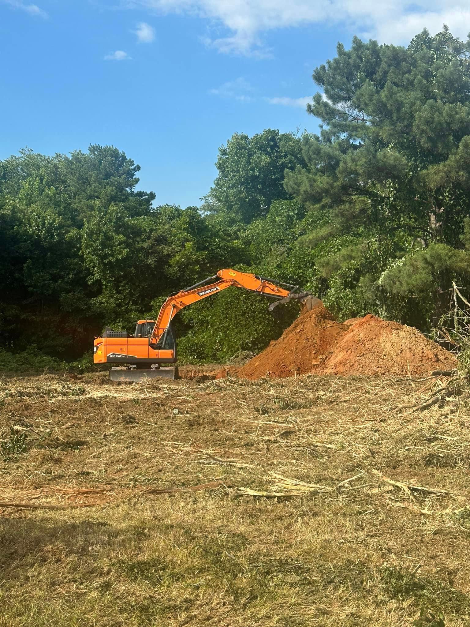 A large orange excavator is moving dirt in a field.