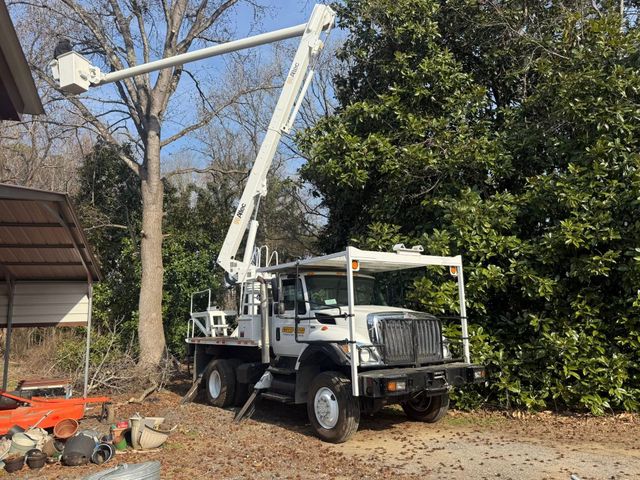 A yellow stump grinder is grinding a tree stump in a yard.