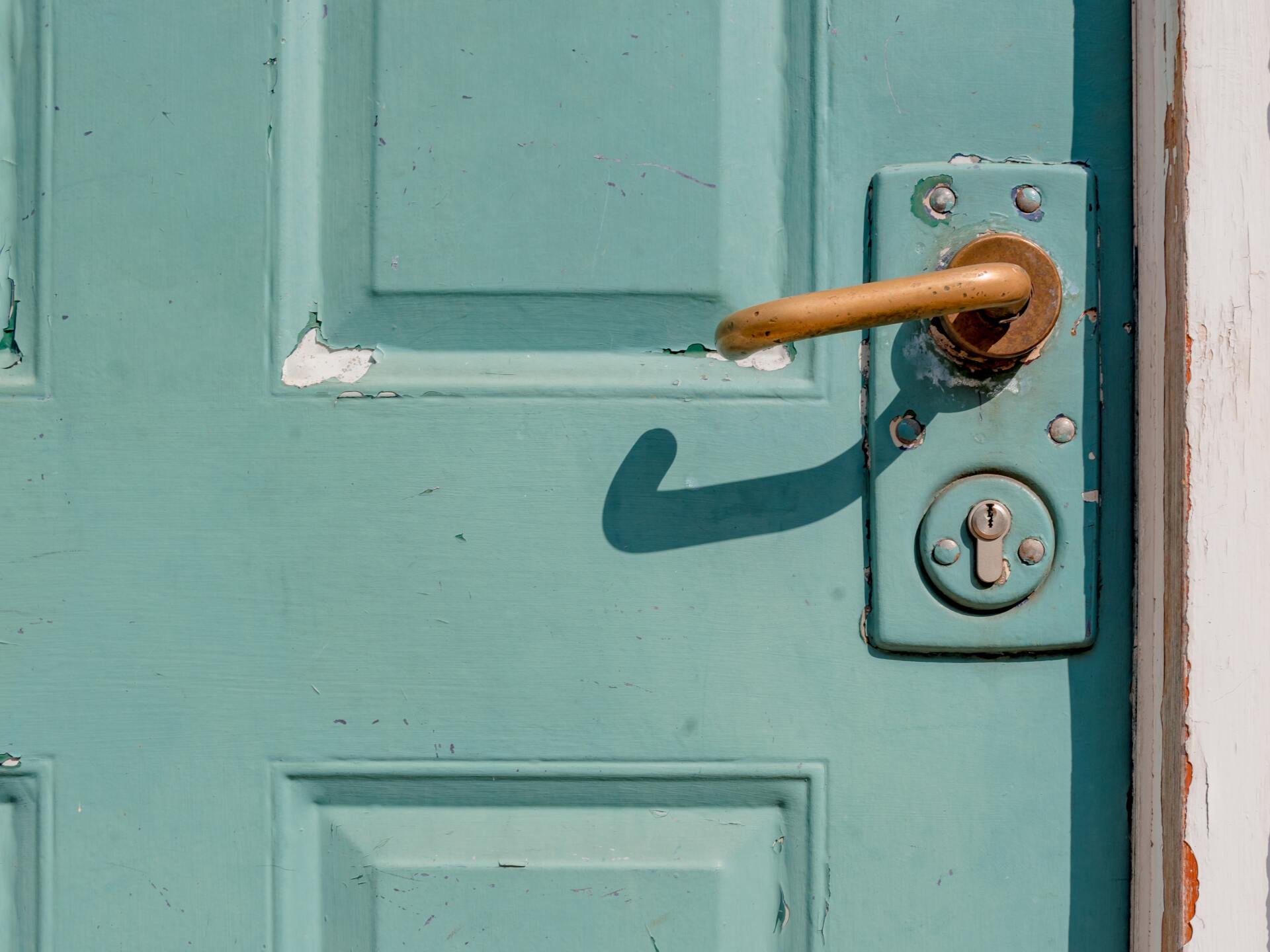 A turquoise door enclosed with a handle and lock featured.