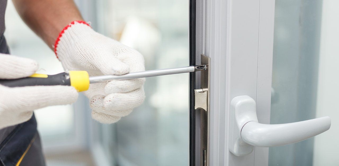 A person attempting to fix a uPVC door lock using a screwdriver.