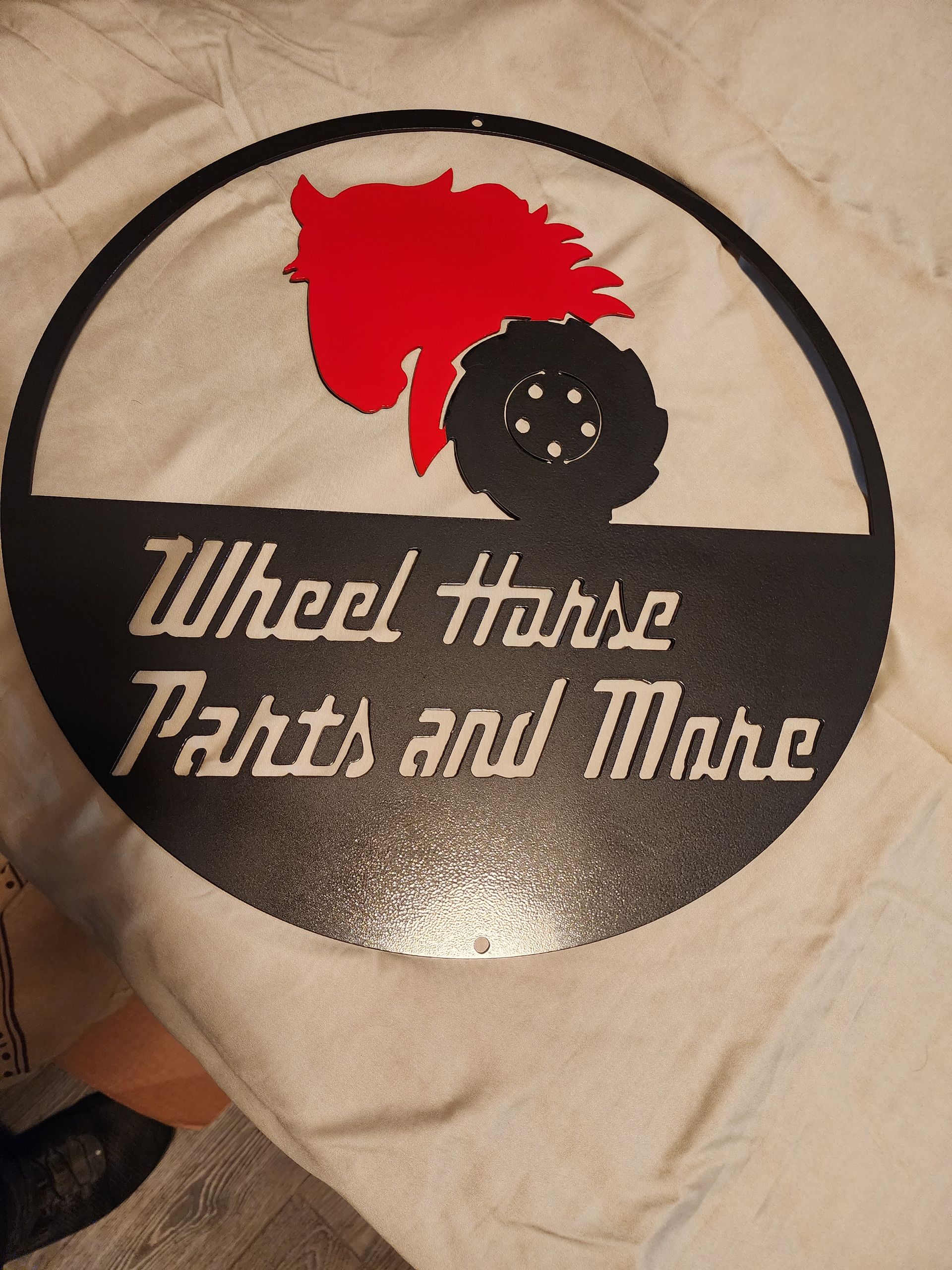 Black metal Wheel Horse sign with red horse head and tire silhouette. 
