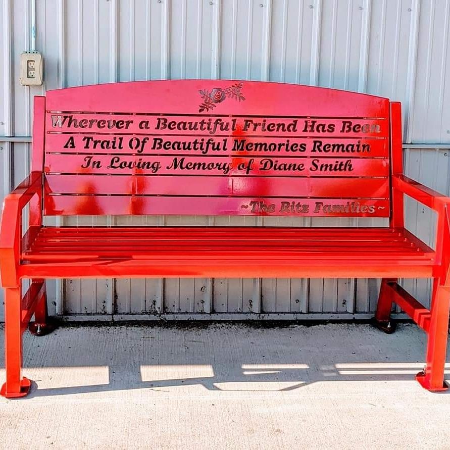 Red memorial bench with engraved inscription, 