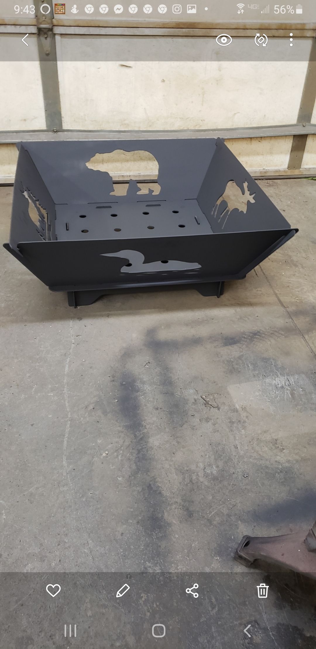 Black, geometric fire pit with cut-out designs sits on a concrete surface.