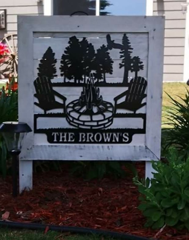 Sign with cut-out silhouettes of a campfire scene, reading 