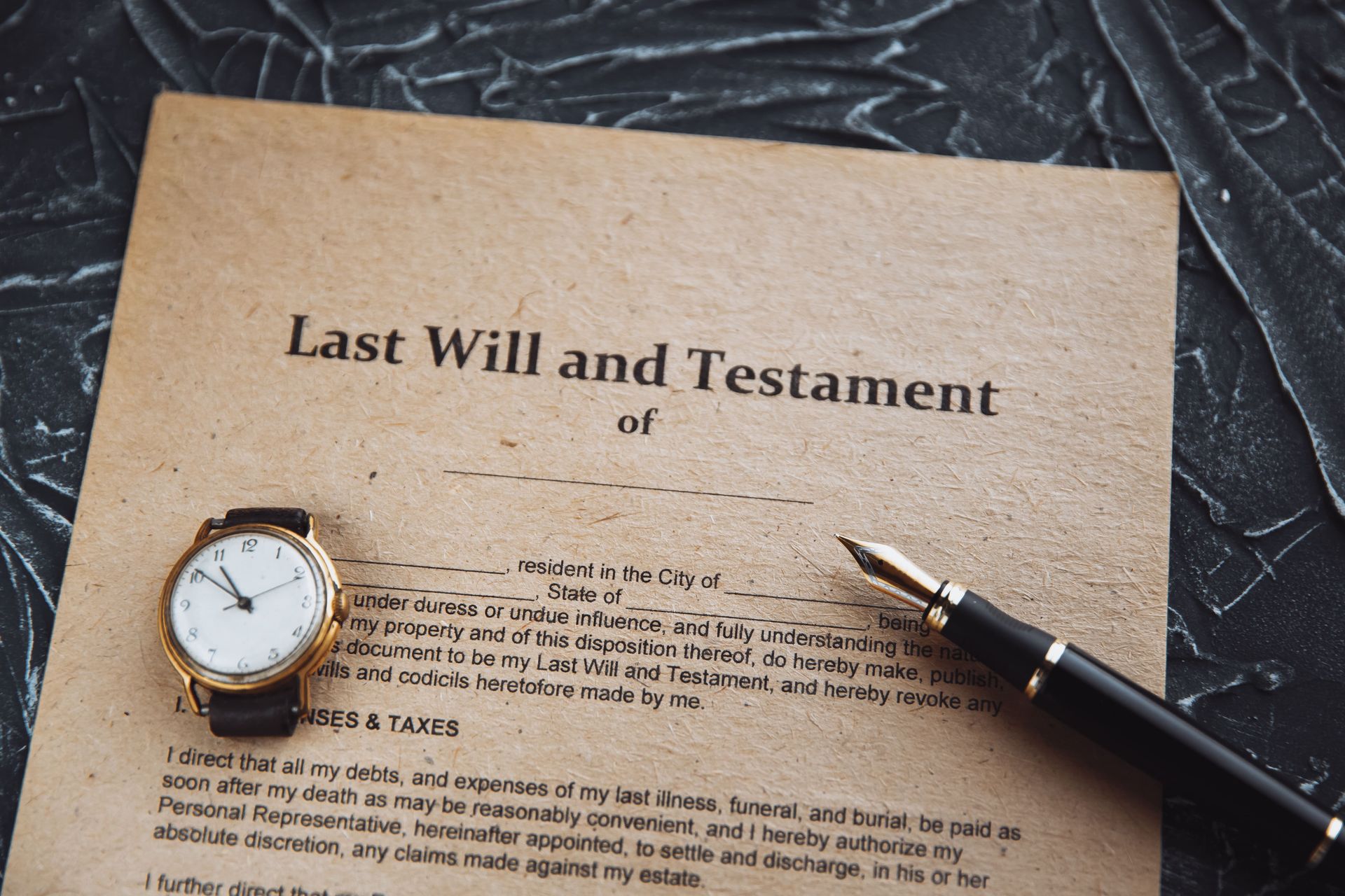 Last Will and Testament document with a pen and watch on a textured surface.
