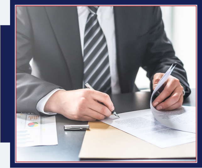 Businessperson signing a document at a desk with papers and a pen