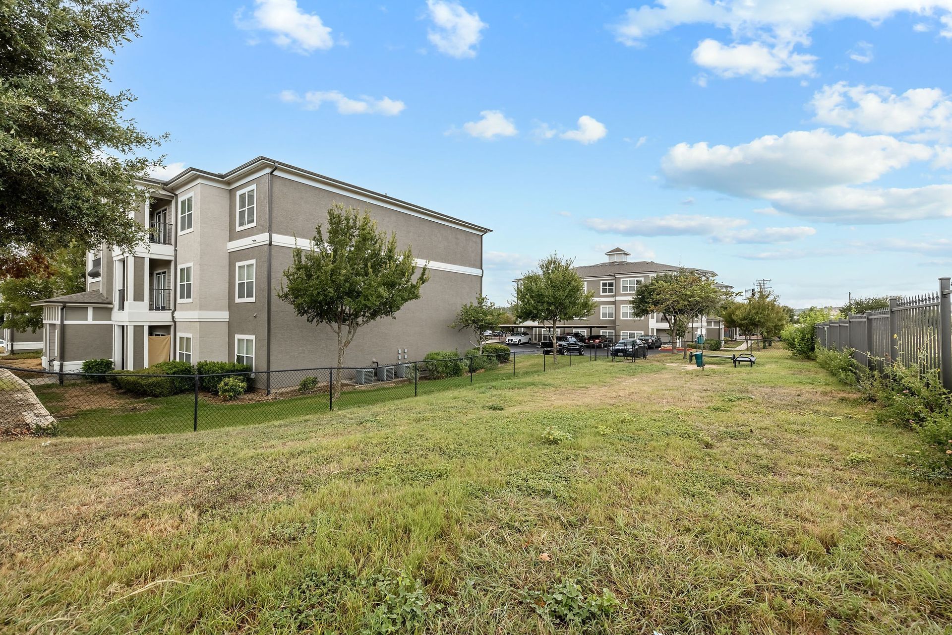 a grassy area with trees and buildings in the background