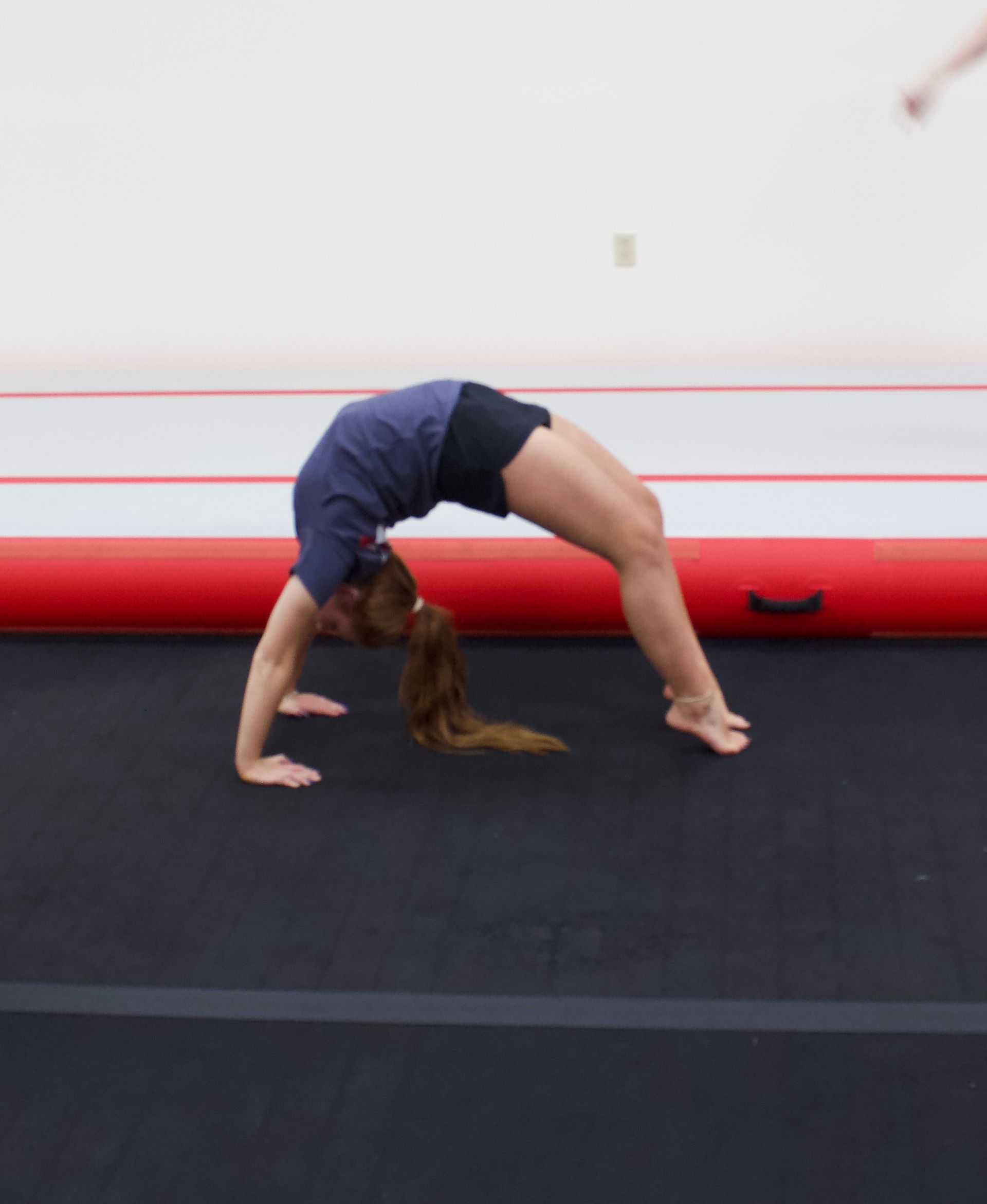 A gymnast in a purple leotard is standing on a balance beam