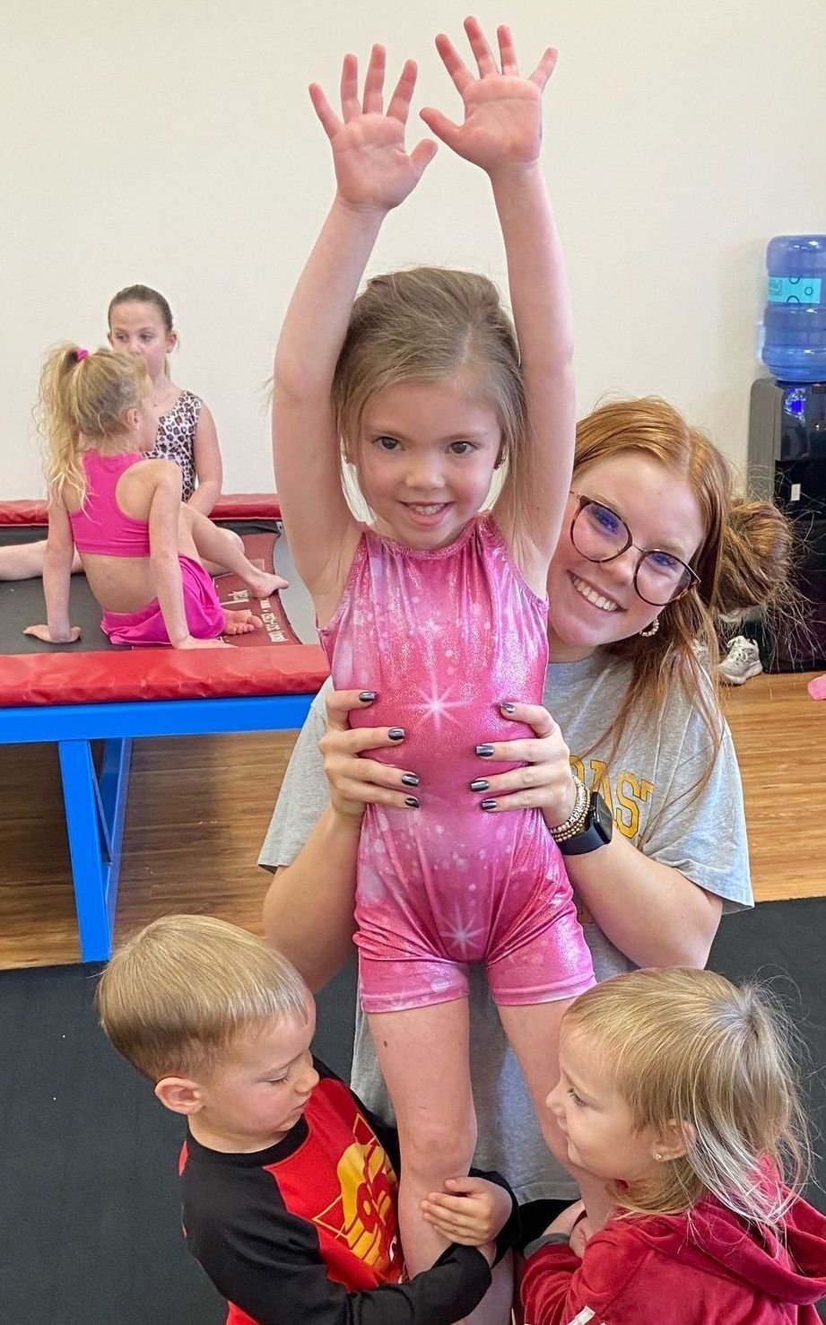 A woman is laying on a yoga mat holding a baby on her lap.
