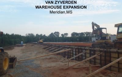 Warehouse expansion construction in Meridian, MS. Heavy machinery, dirt, and wooden supports.