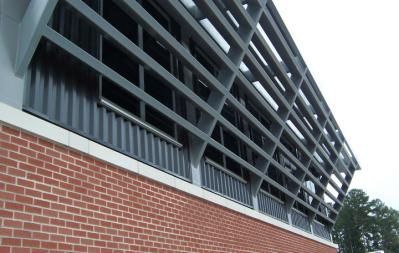Red brick building with gray metal latticework and corrugated panels above the windows.