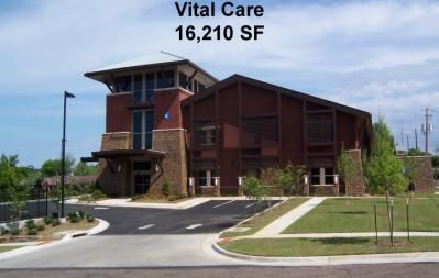 Vital Care clinic with brick and brown exterior, parking lot, and manicured lawn.