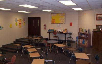 Classroom with desks, stage, door, and books.