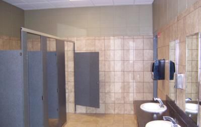 Public restroom with tile walls and floors, stalls, sinks, and mirrors.