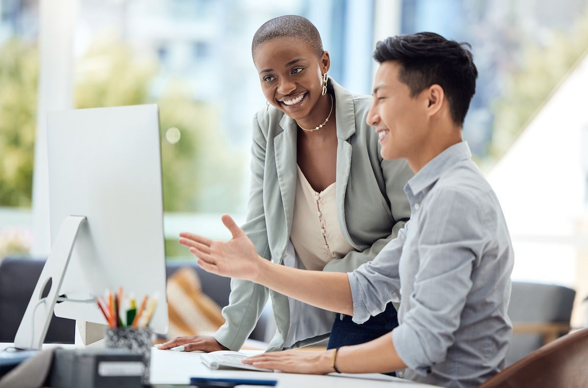 Um homem e uma mulher estão olhando para a tela de um computador.