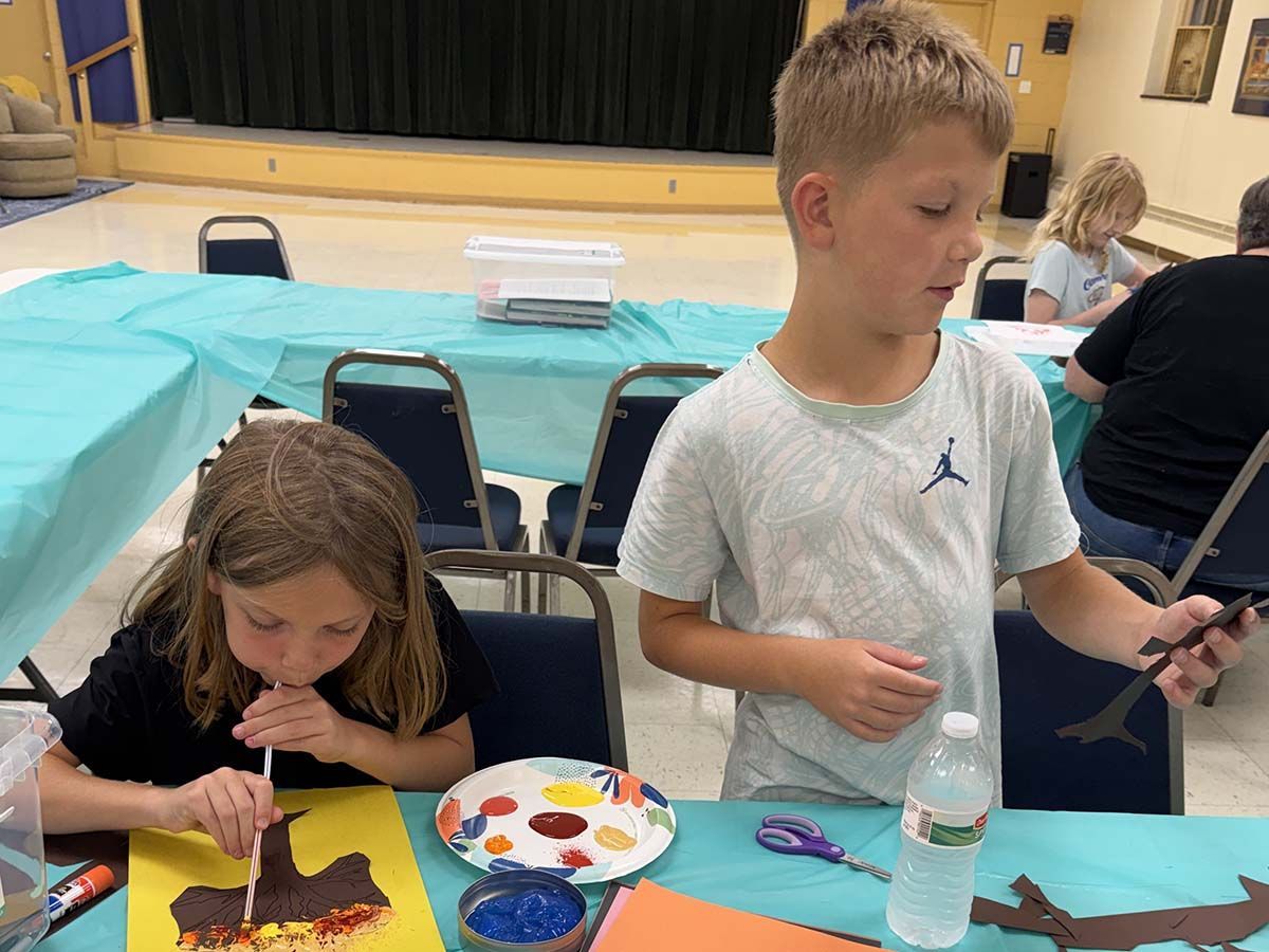 Two children painting at a table beside an indoor swimming pool