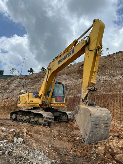 Yellow excavator on a rocky construction site under cloudy sky