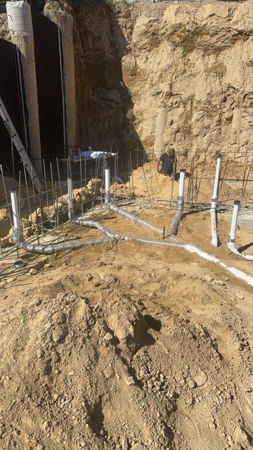 Excavation trench with exposed pipes and dirt walls at a construction site