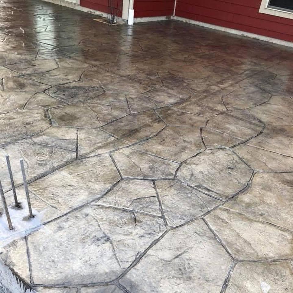 Stamped concrete patio with stone pattern and a red building wall in the background