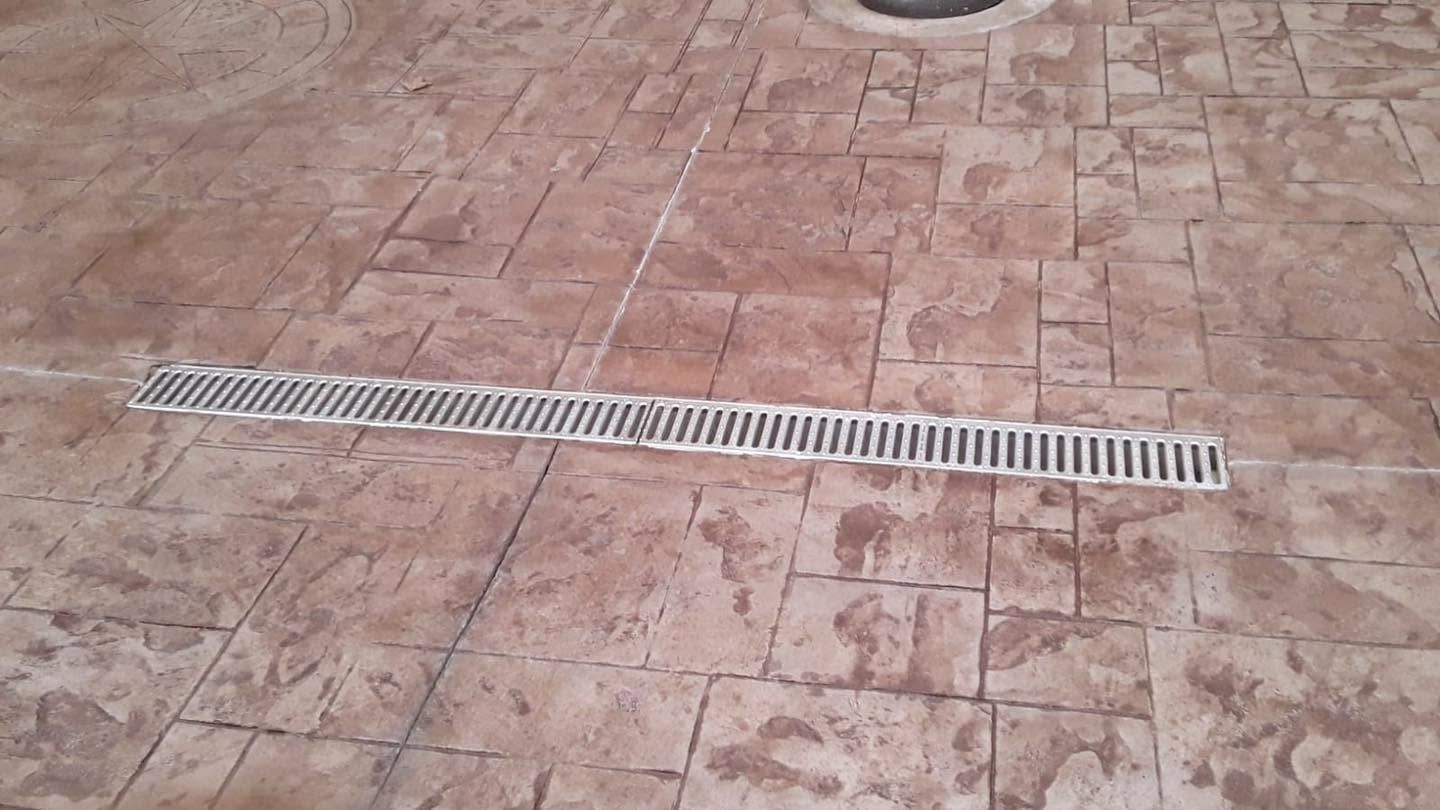 Tiled floor with a long metal drain grate across the center.