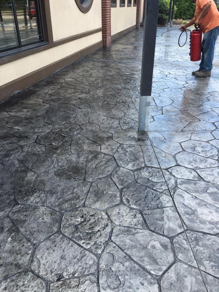 Wet patterned stone walkway beside a building, with a red fire extinguisher mounted on a post.