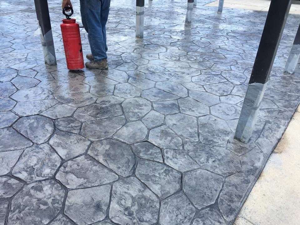 Person walking on a stone pavement carrying a red fire extinguisher