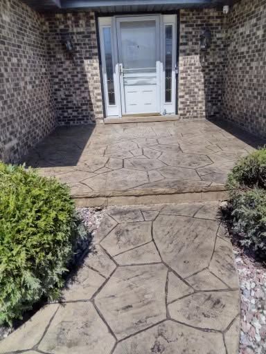 Stone walkway leading to a white front door with brick walls and shrubs on either side