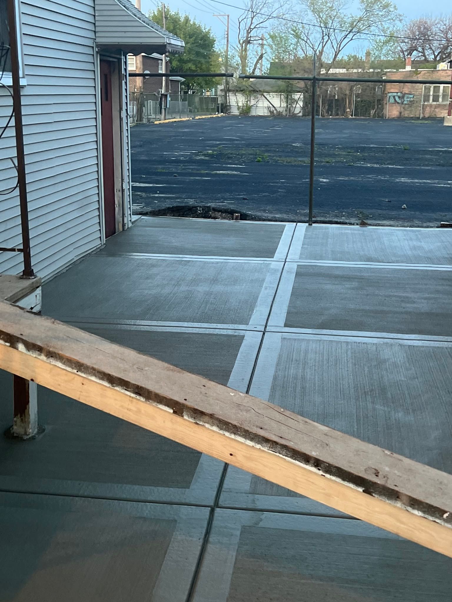 Backyard patio with a wooden ramp leading to a concrete slab and fenced yard.