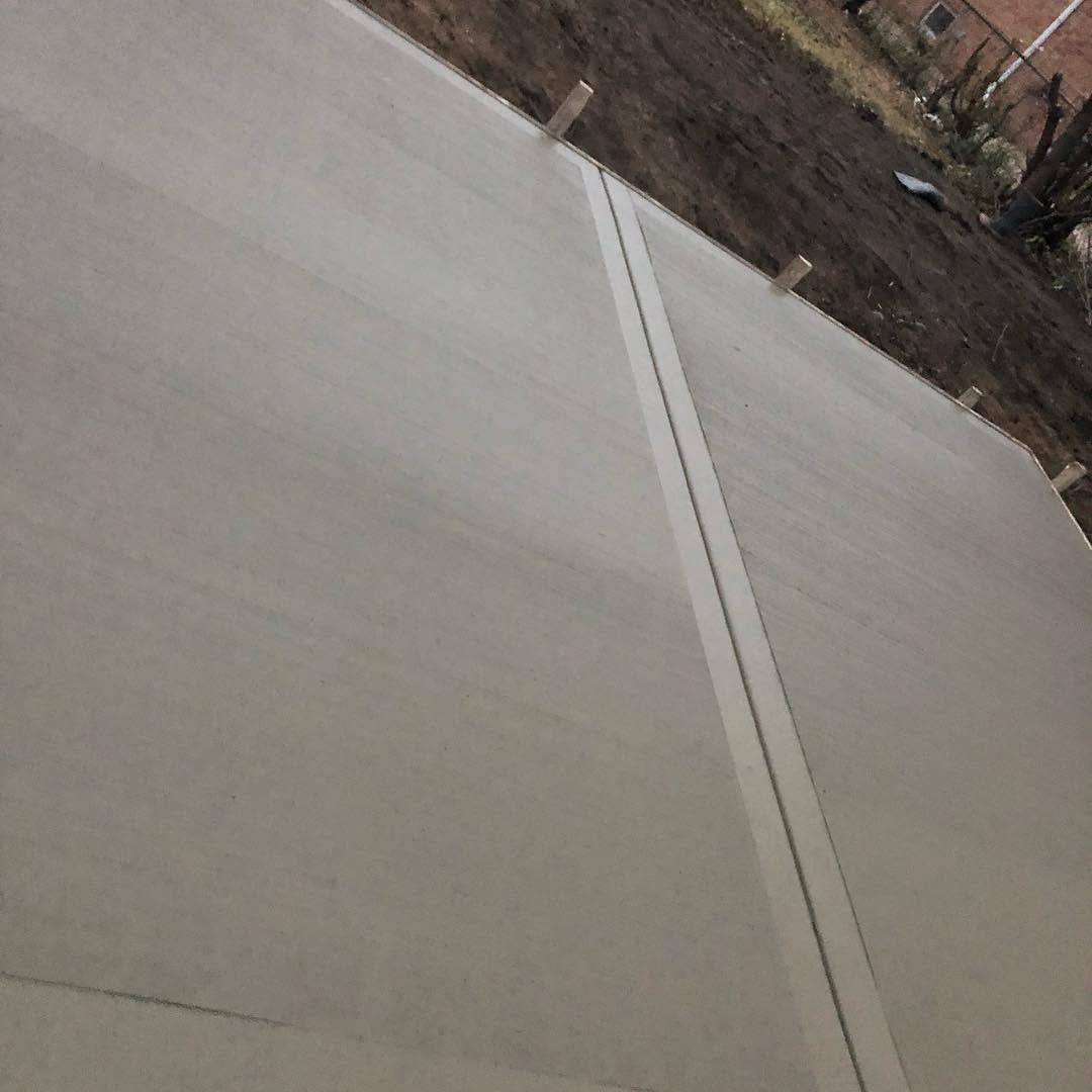 Tilted view of a concrete road or sidewalk with a center seam and dirt shoulder at the edge