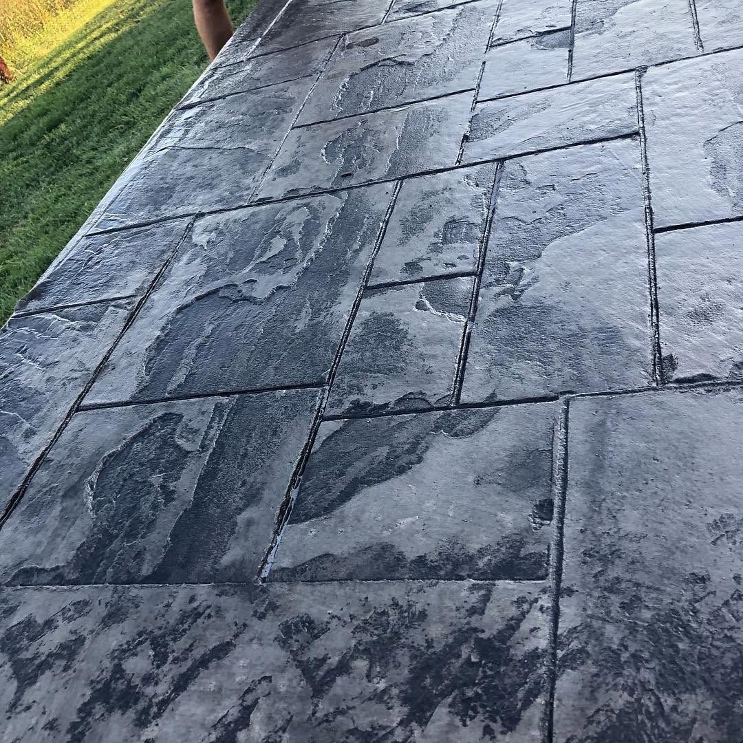 Gray stone pavers beside a grassy edge, viewed at a slight angle outdoors.