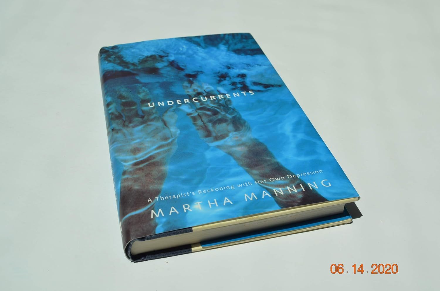 Blue book lying on a table, with an orange date stamp in the lower right corner.